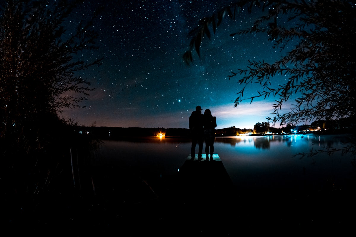 A couple silhouetted beneath a night sky